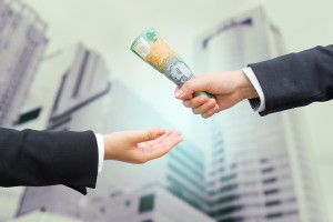 Hands of businessman passing Australian dollar (AUD) banknote wi