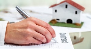 Hand Filling Out House Buying Contract.