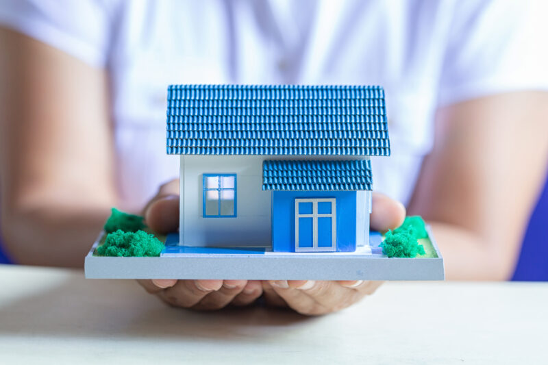 Human Hands Holding Model Of Dream House, Loans And Investments
